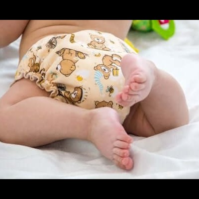 Fralda reutilizável bege com estampado de ursos castanhos e bebé deitado