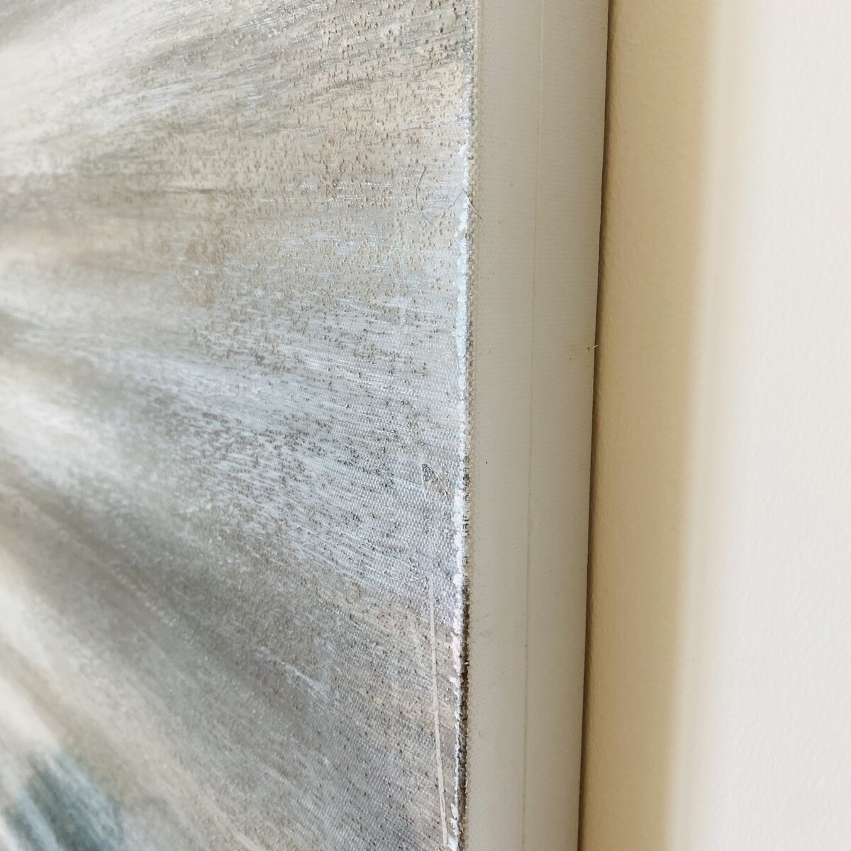 Tela artística com texturas cinza e bege emoldurada e pendurada numa parede clara