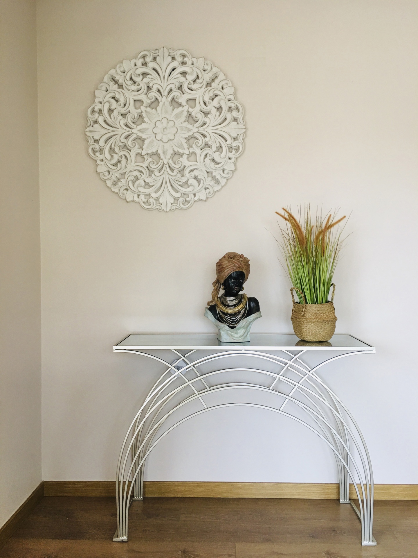 Mesa de consola branca com busto decorativo, vaso de plantas e mandala na parede