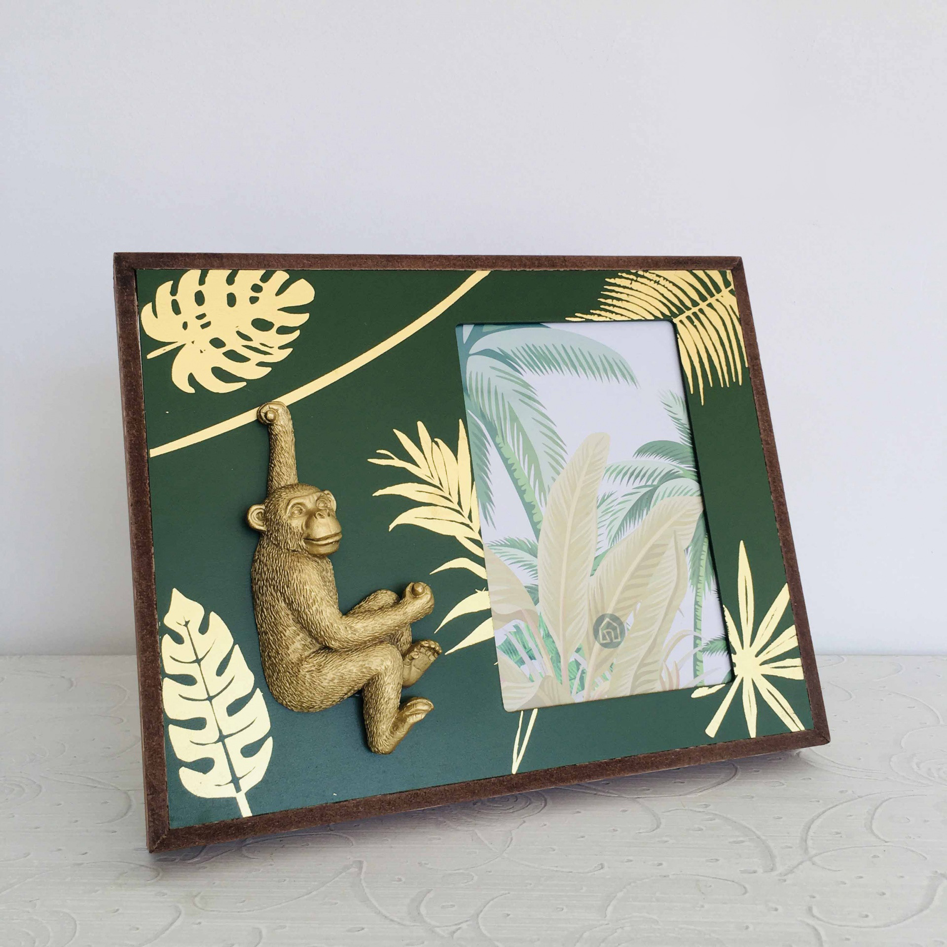 Porta-retrato verde com folhas douradas e figura de macaco dourado em madeira
