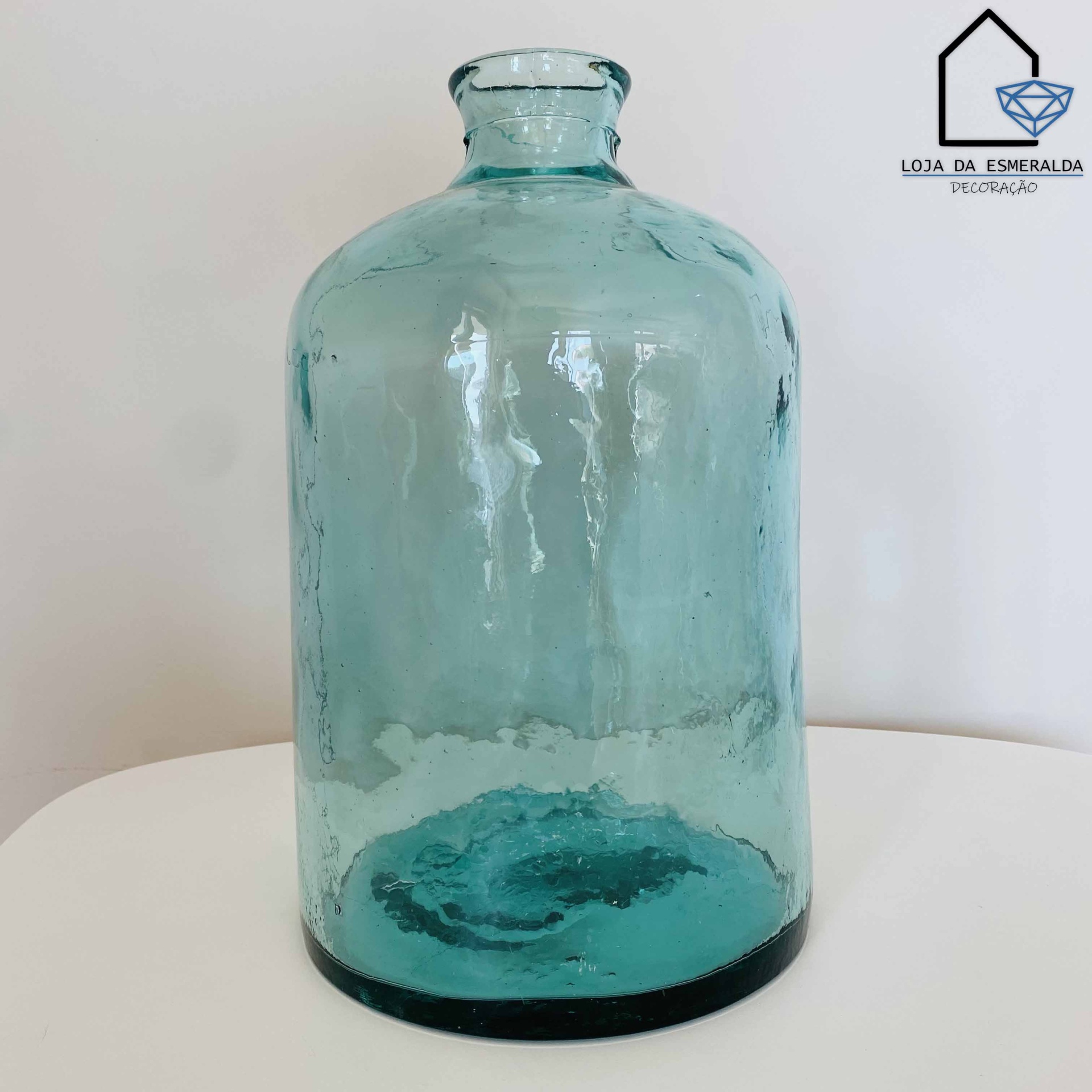 Garrafa de vidro azul claro decorativa com texturas, sobre superfície branca