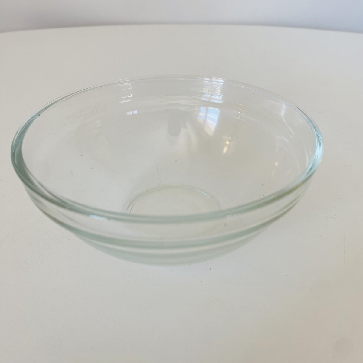 Taça rasa transparente em vidro sobre superfície branca