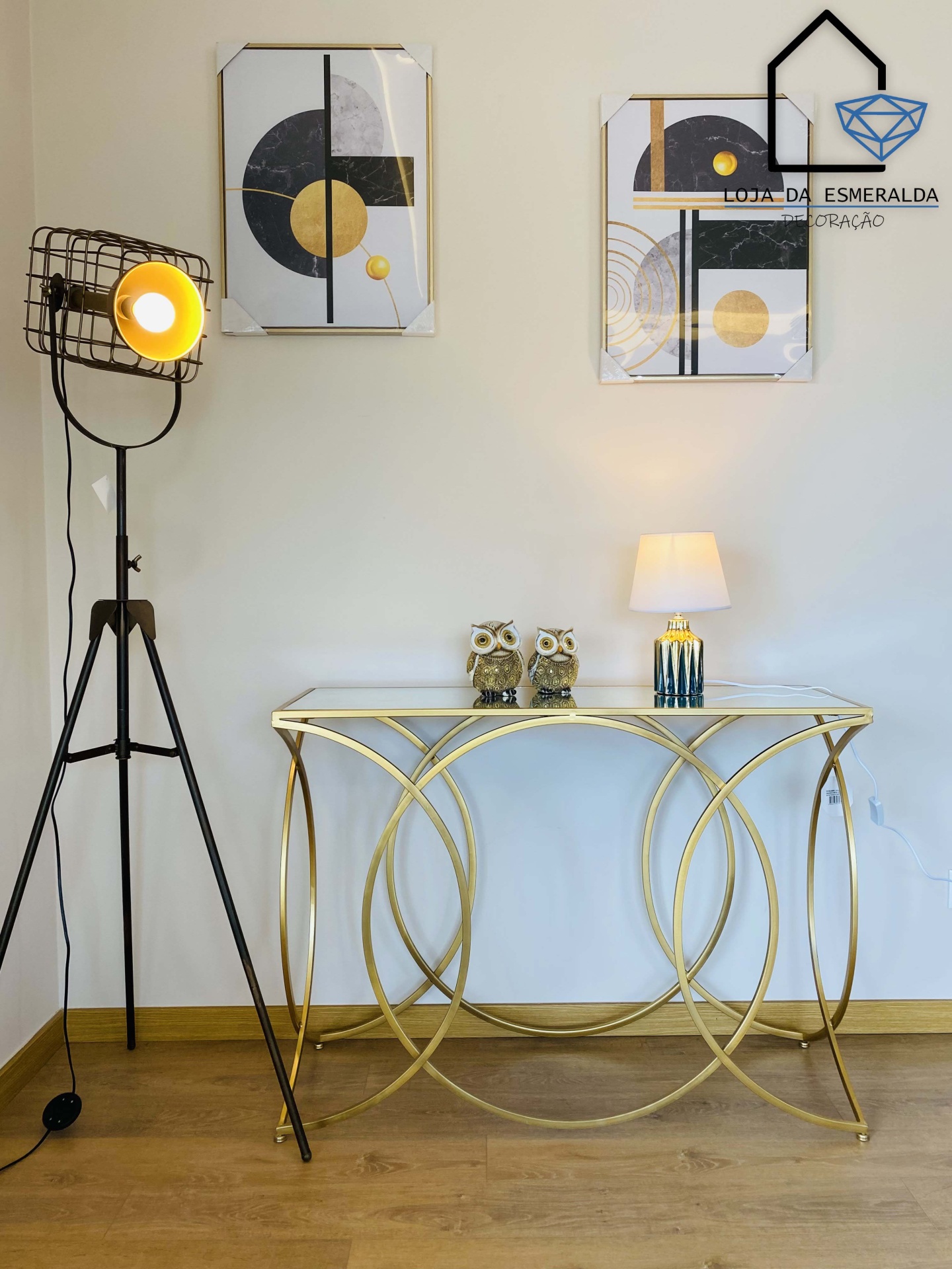 Conjunto decorativo minimalista com telas geométricas, candeeiro de pé preto, consola dourada com vidro e corujas decorativas