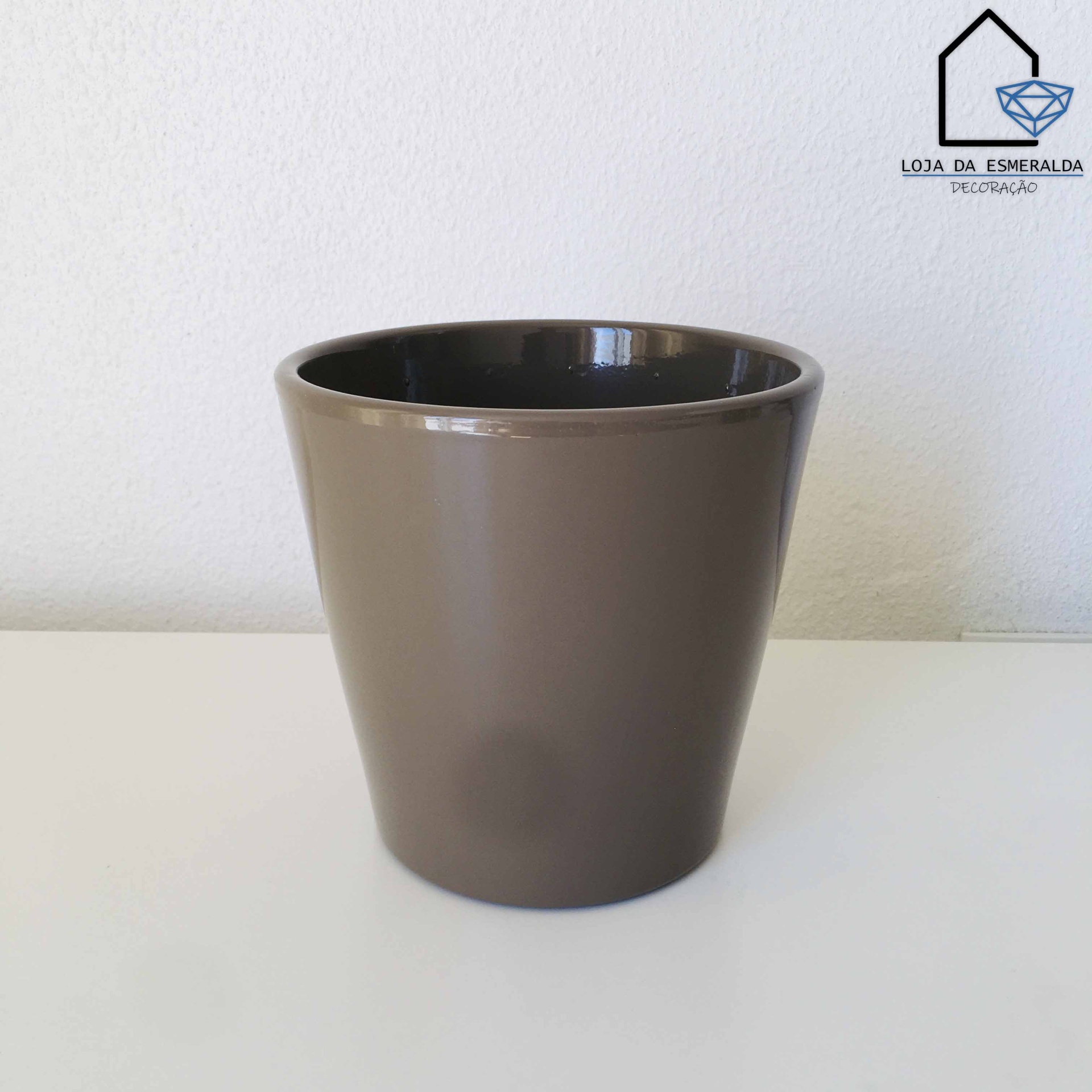 Vaso cilíndrico castanho com interior castanho escuro sobre superfície branca