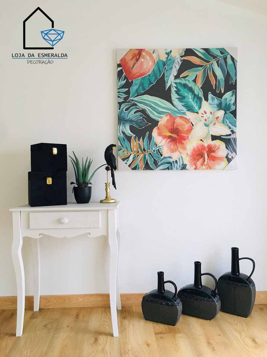 Mesa branca com caixas, planta, pássaro decorativo, quadro de flores e jarros pretos no chão