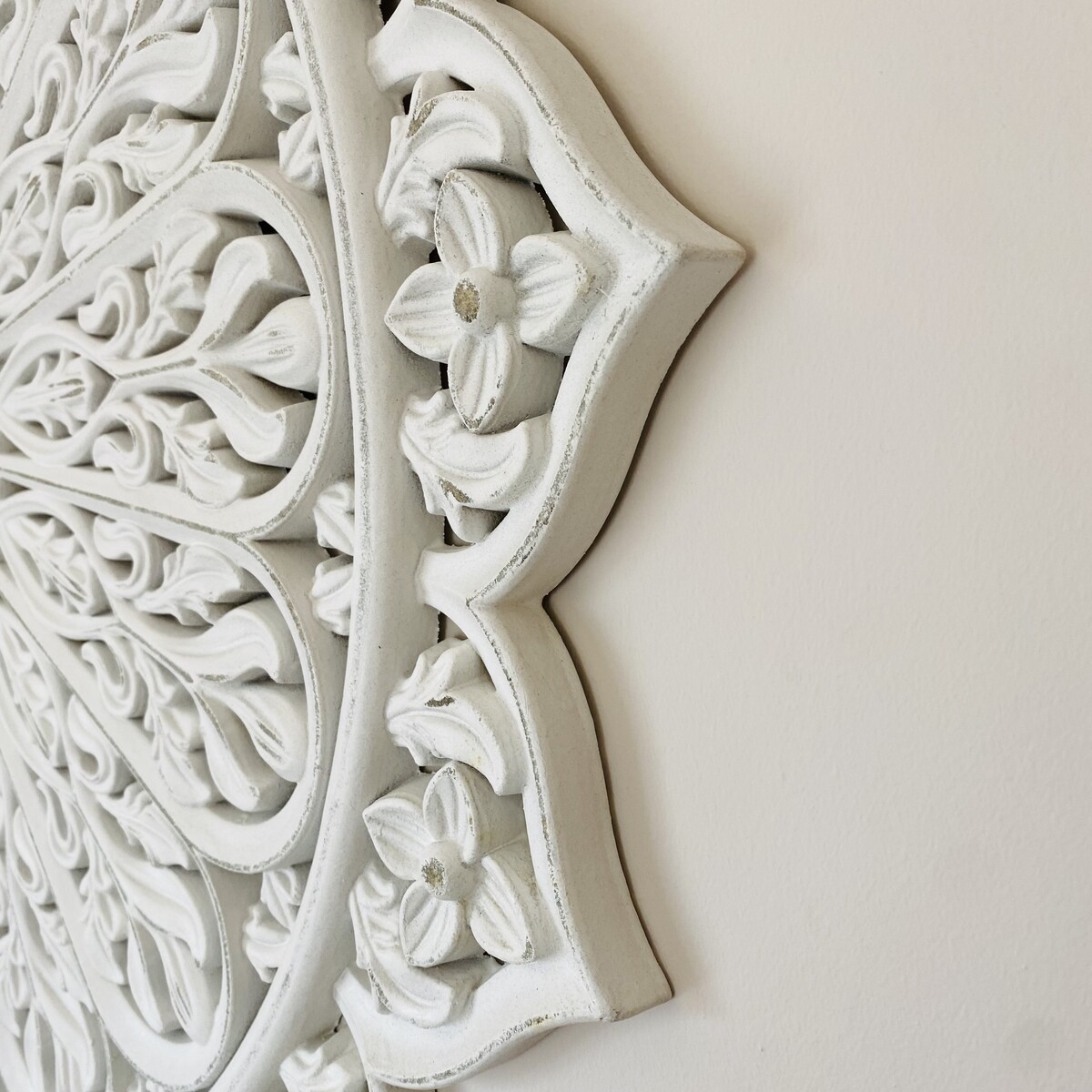 Elemento decorativo de parede em madeira branca com padrão floral entalhado