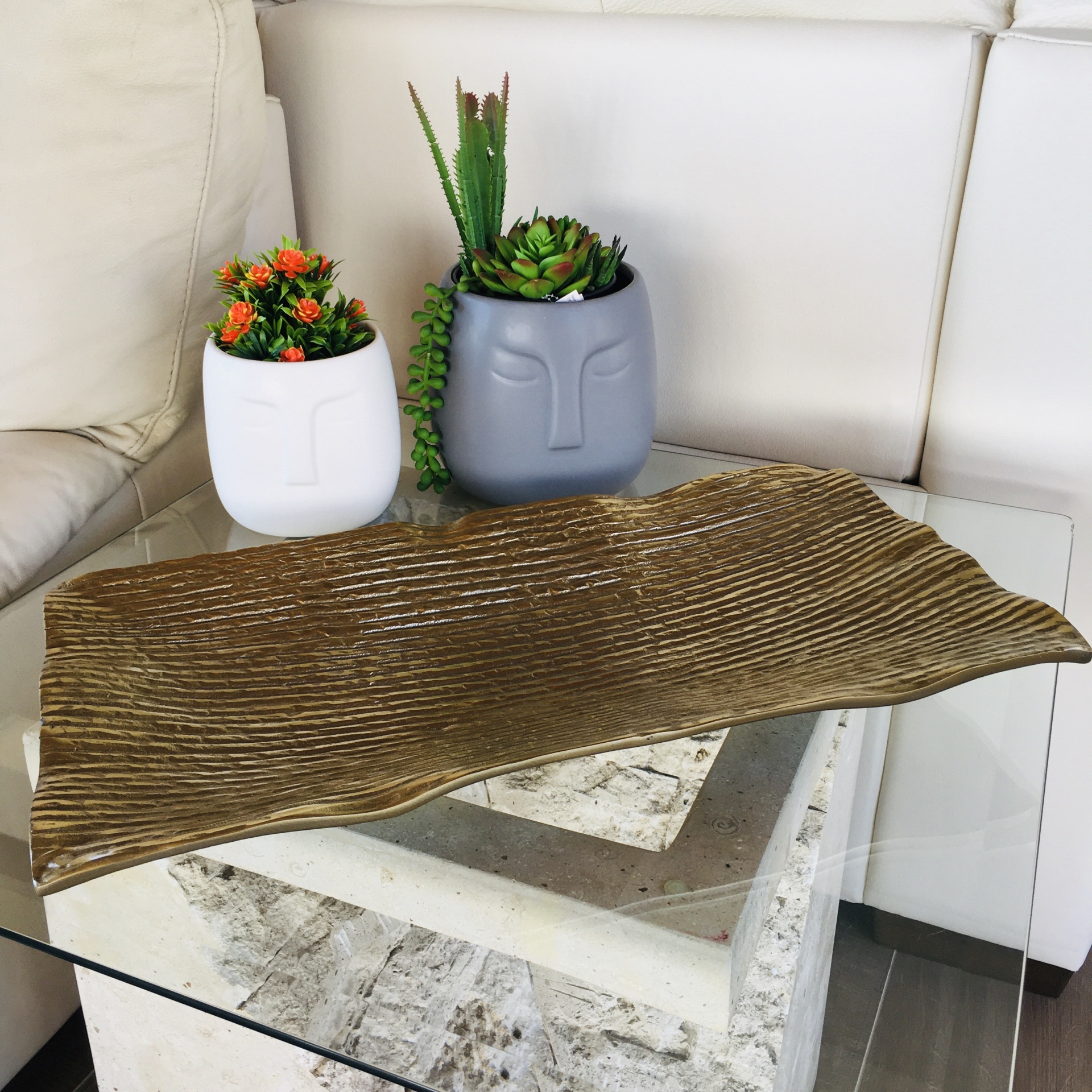 Dois vasos cerâmicos com plantas sobre mesa de vidro e centro de madeira ondulado