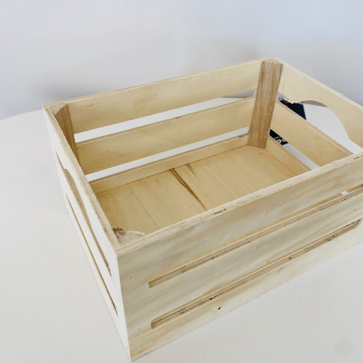 Caixa de madeira clara com ripas horizontais e manípulos recortados