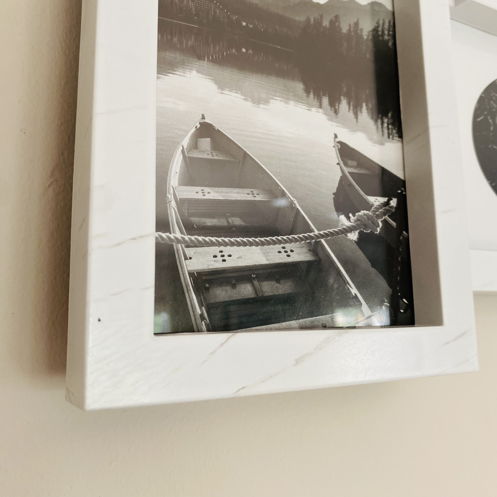 Fotografia a preto e branco de dois barcos numa moldura branca com efeito mármore