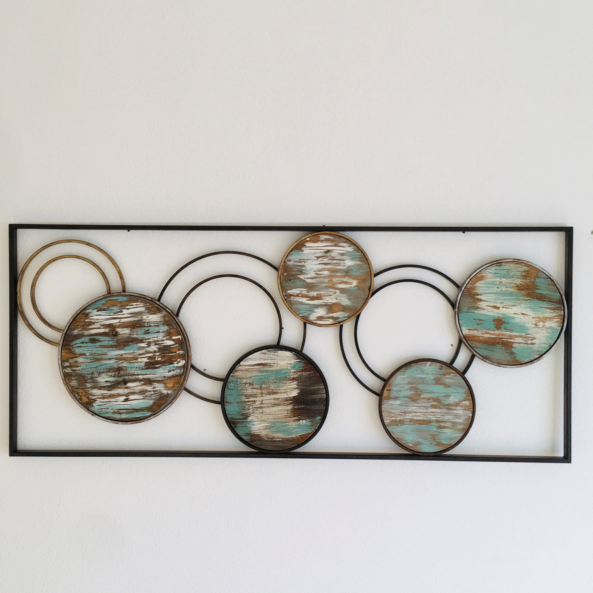Painel decorativo metálico e madeira com círculos azuis e castanhos na parede