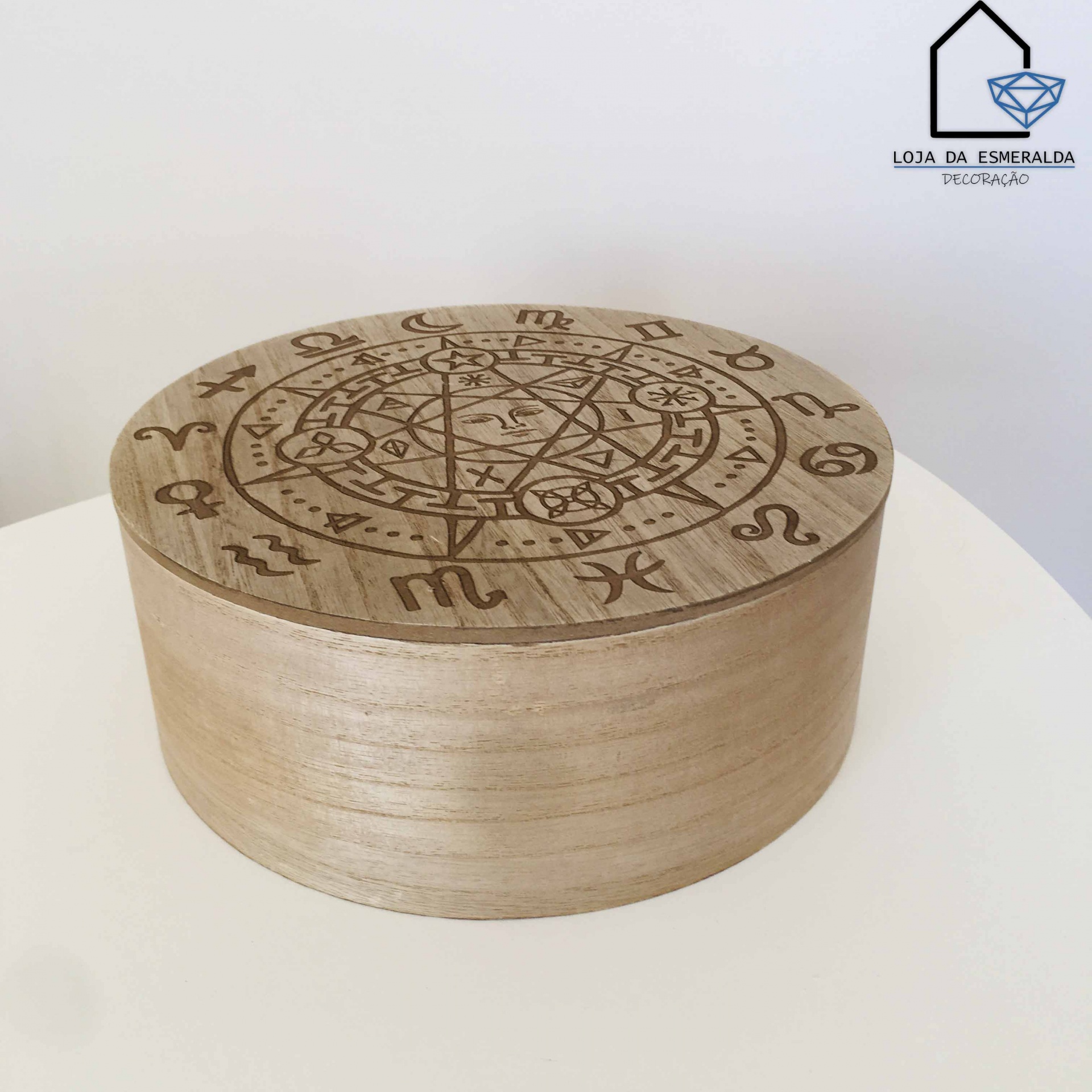 Caixa redonda de madeira clara com símbolos do zodíaco gravados na tampa