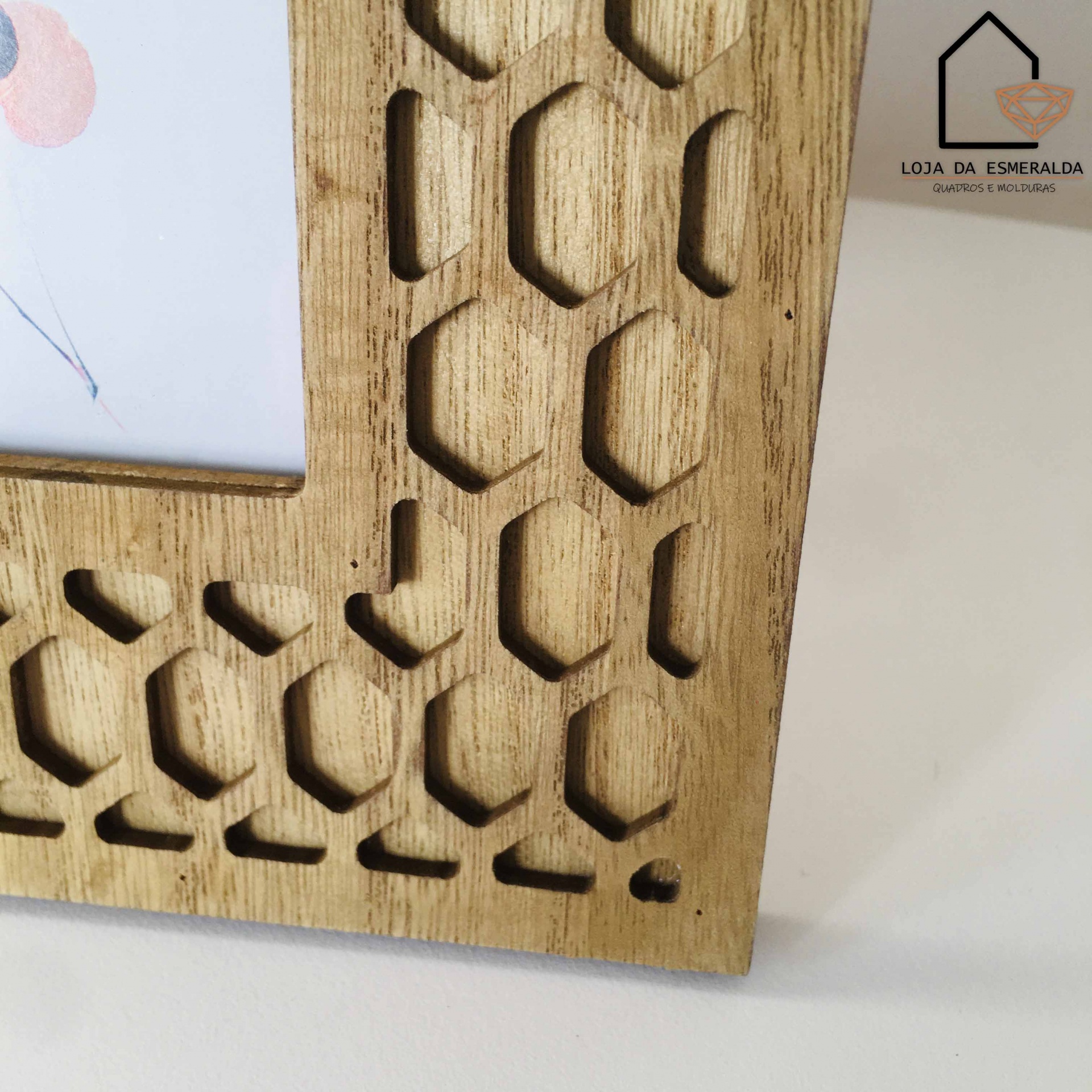 Moldura de madeira clara com padrão geométrico e etiqueta LOJA DA ESMERALDA
