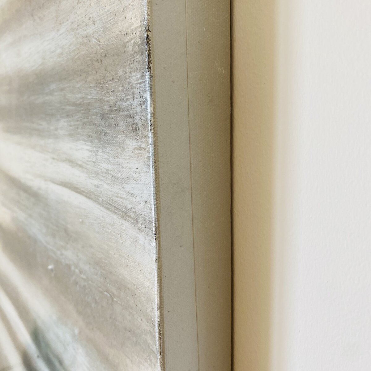 Close-up de moldura branca com superfície texturizada cinza e bege na parede branca