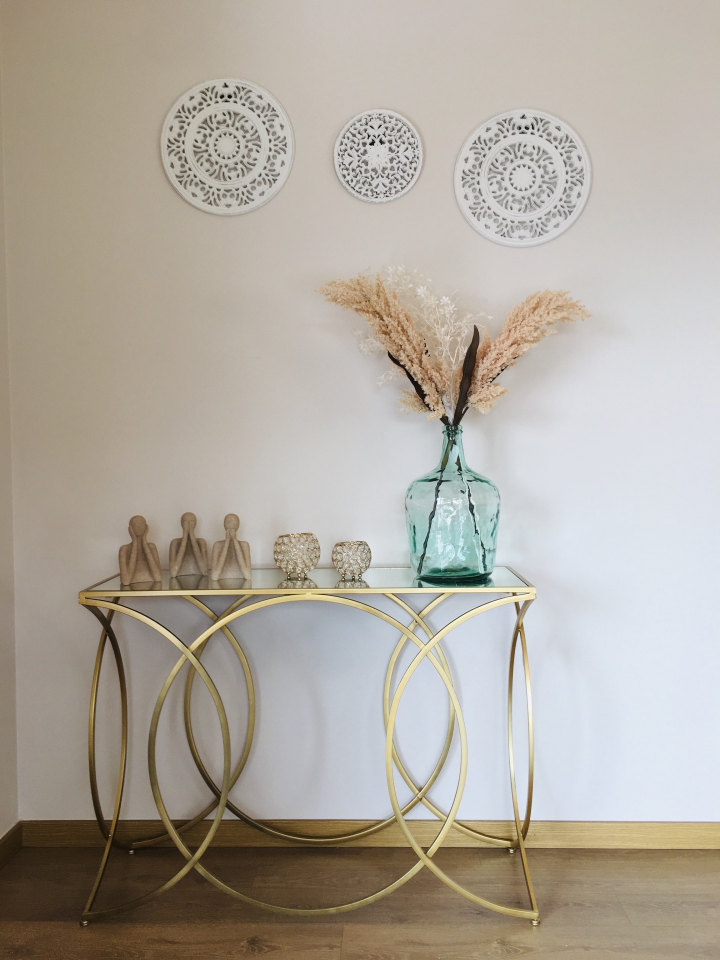 Mesa de apoio dourada com decorações e placas decorativas redondas na parede