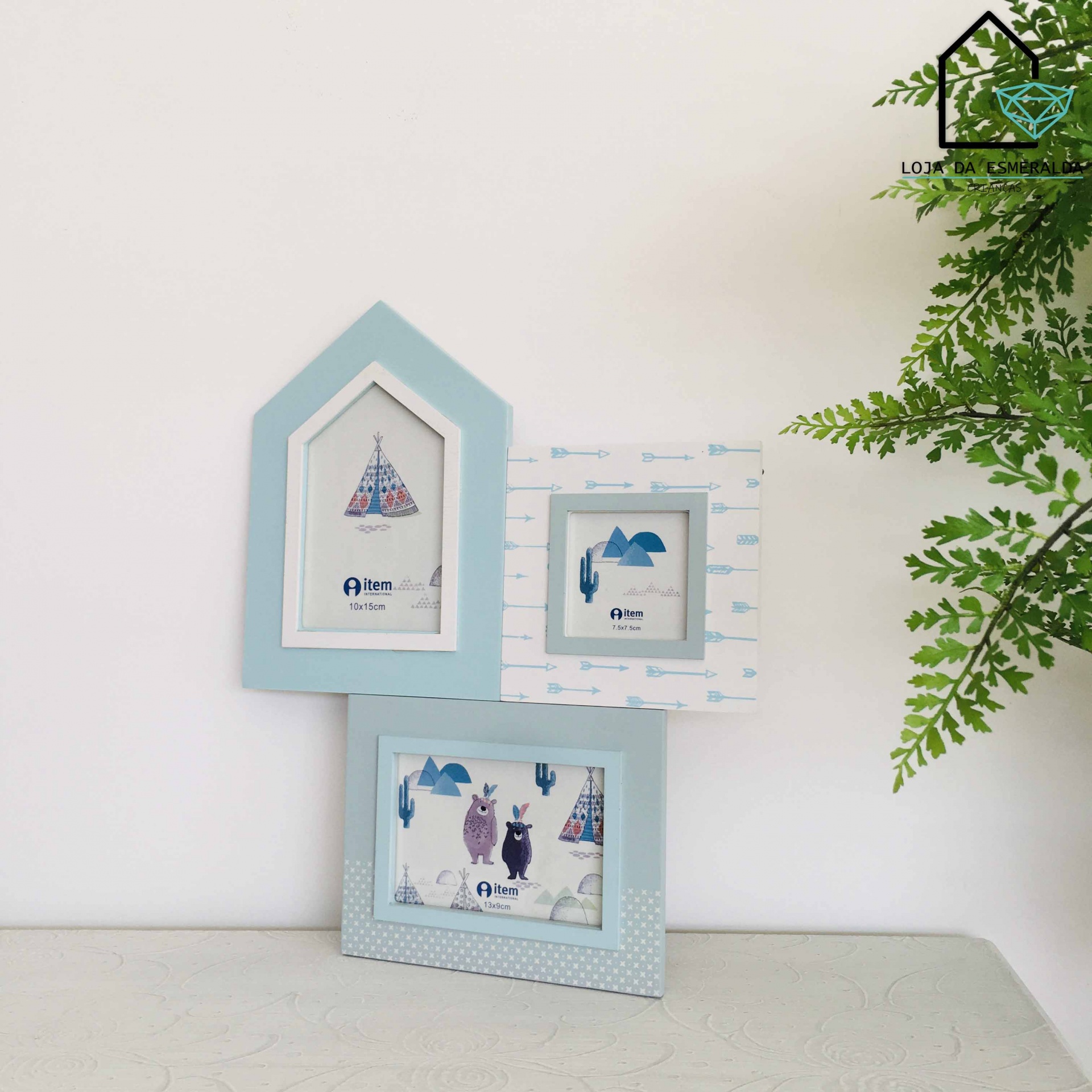 Três molduras de fotos decorativas em tons de azul e cinza com imagens de tenda, cacto e bichos, junto a uma planta verde.