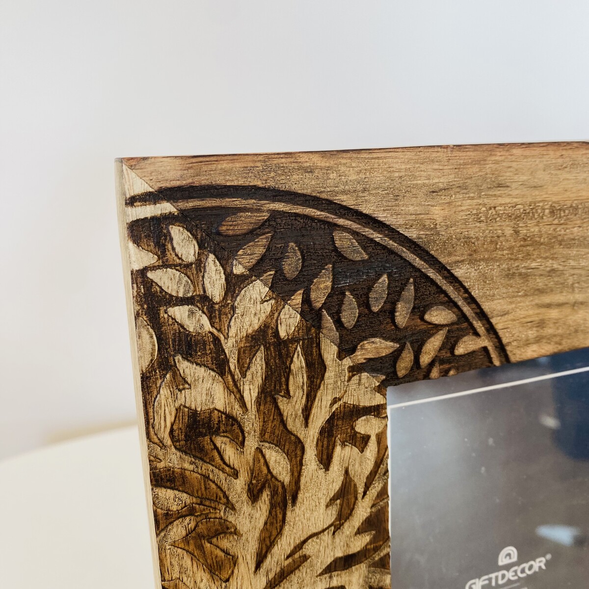 Canto de moldura de madeira com padrão gravado de folhas e ramos