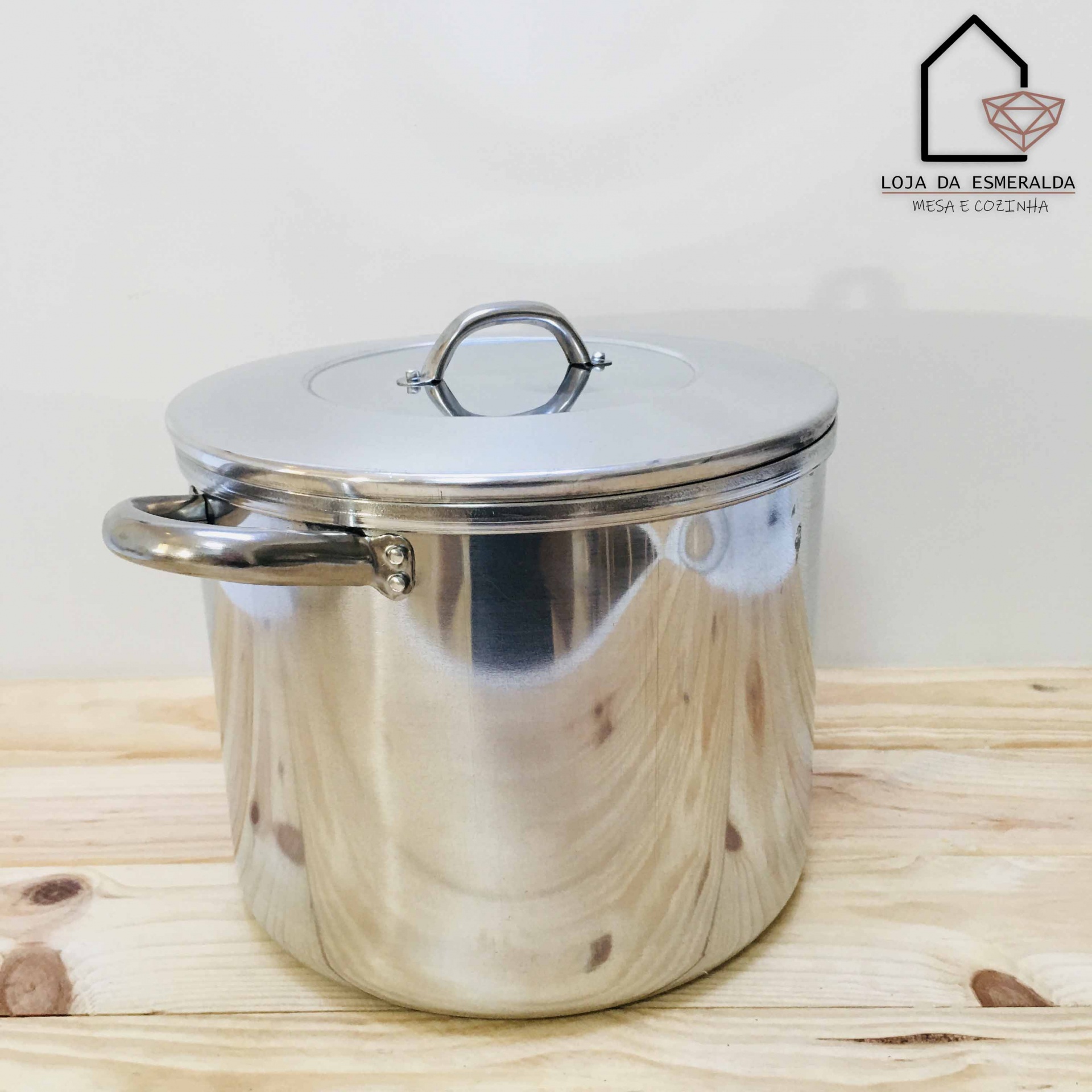 Panela de aço inoxidável com tampa sobre superfície de madeira clara