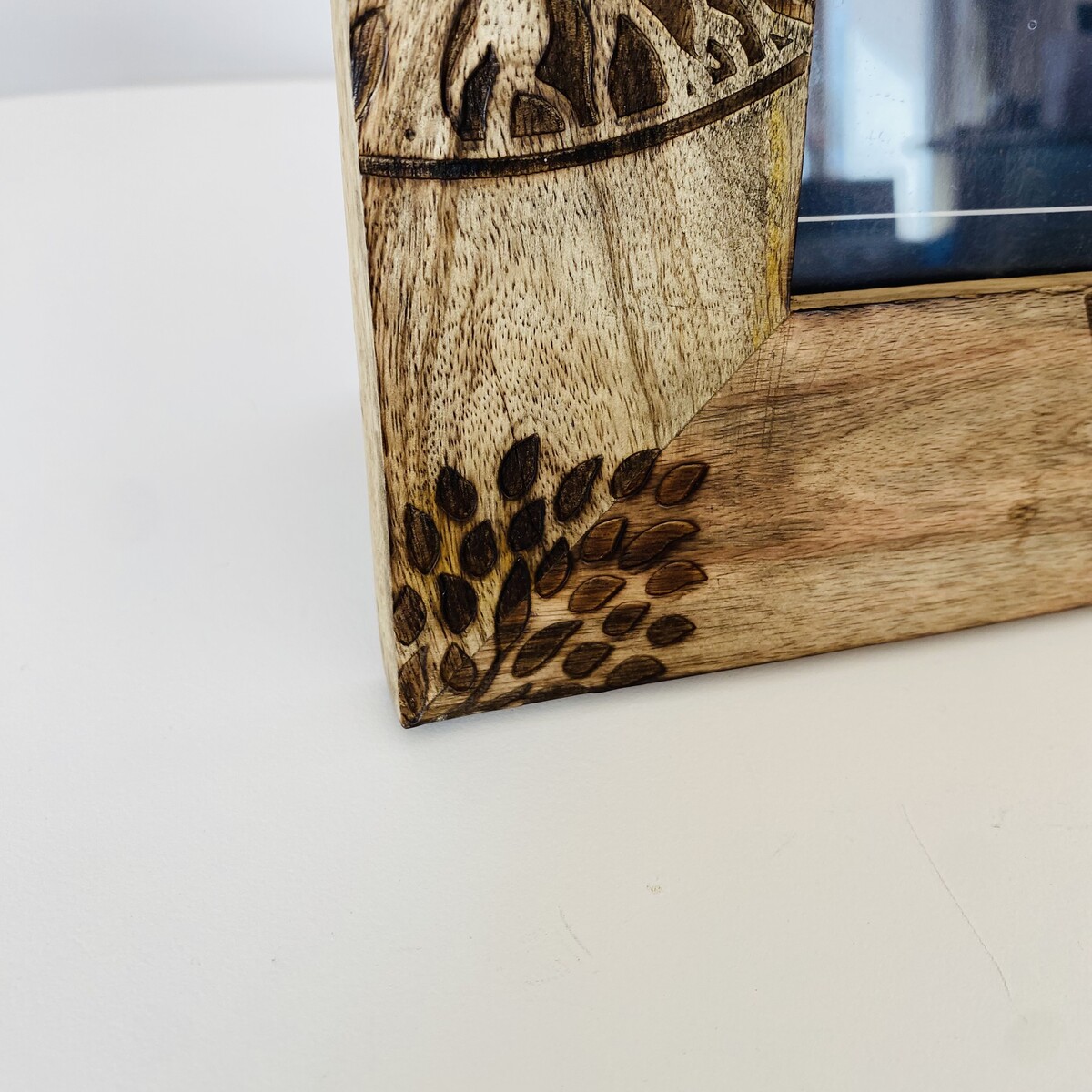 Canto decorativo de moldura de madeira clara com padrão esculpido em folhas