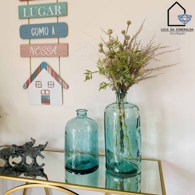 Dois vasos de vidro azul translúcido com decoração e placas de madeira coloridas na parede