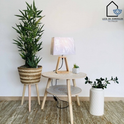 Mesa redonda de madeira com plantas e candeeiro numa decoração minimalista