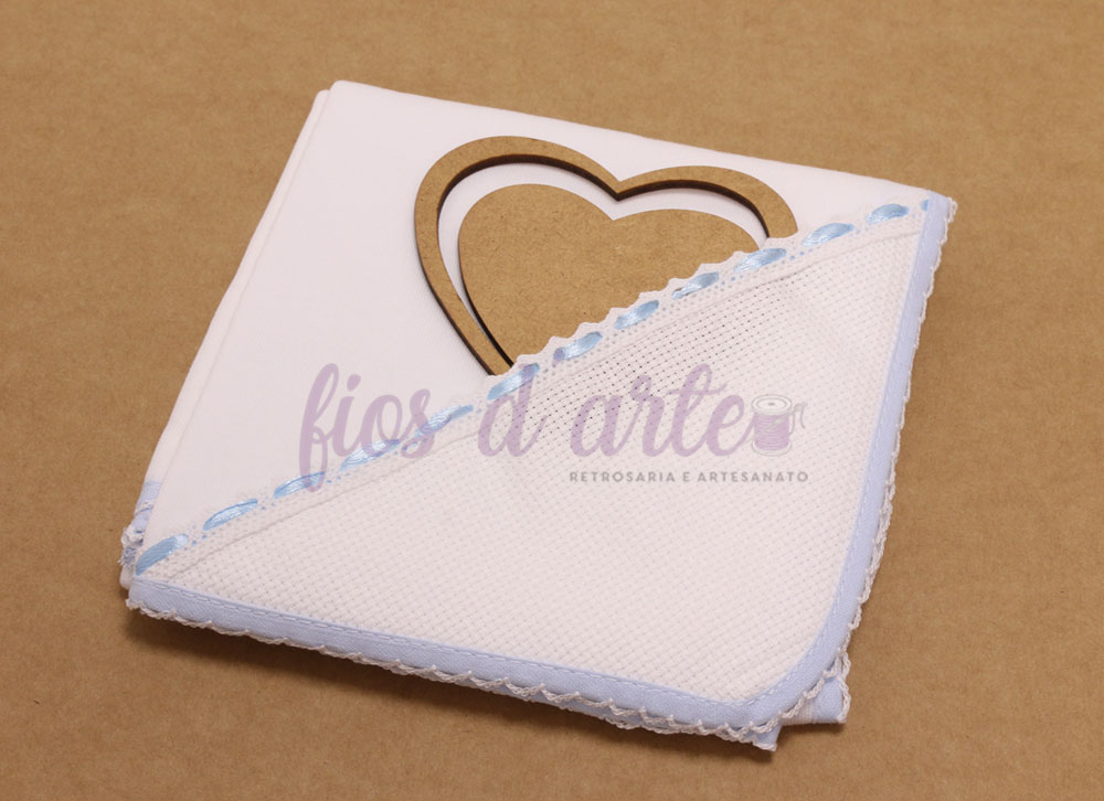 Fralda para bebé com fita de cetim para bordar ponto cruz Toalha branca com borda azul e renda com coração de madeira ao fundo
