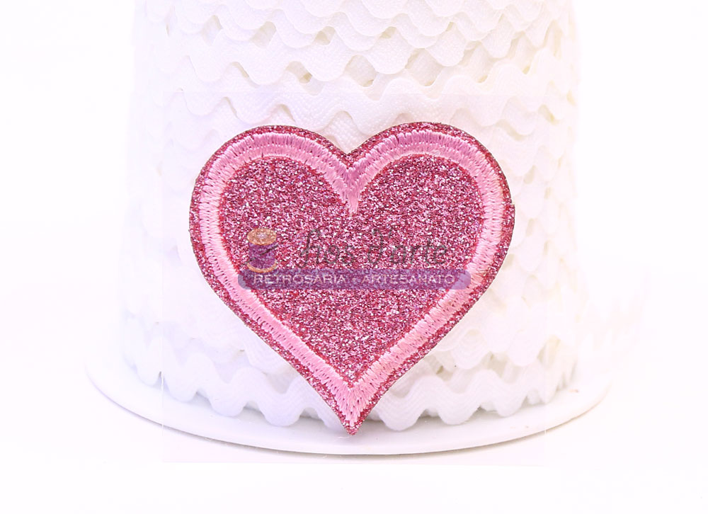 Aplicação termocolante Coração com glitter (4,3x4,5cms) - rosa Adesivo cor-de-rosa brilhante em forma de coração sobre fundo branco texturizado.