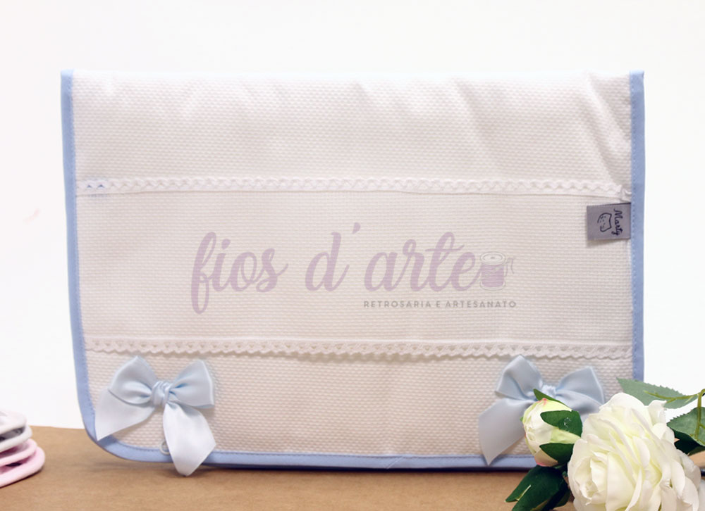 Toalha branca com borda azul e laços, texto 'fios d'arte' e flor branca ao lado