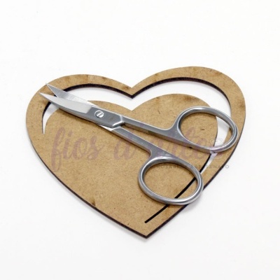 Tesoura pequena de metal prateado sobre suporte em forma de coração castanho