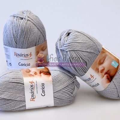 Três novelos de fio cinza claro com rótulos Rosários 4 Carícia