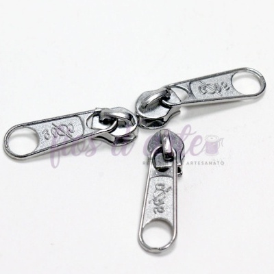 Três puxadores de metal prateados para fecho éclair sobre fundo branco