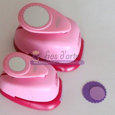 Duas perfuradoras de papel rosa e vermelho com círculos dentados recortados ao lado