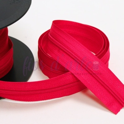 Fita de fecho éclair vermelha enrolada num carretel preto