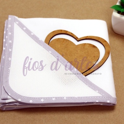 Manta branca com borda lilás de estrelas, coração em madeira e planta suculenta em vaso branco