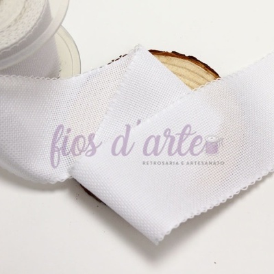 Fita branca texturizada em carretel e desenrolada sobre madeira