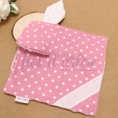 Pano de cozinha rosa com bolas brancas e fita branca sobre mesa castanha clara