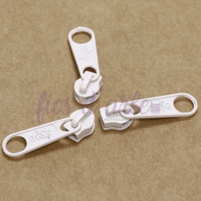 Três cursores de fecho éclair brancos sobre superfície castanha