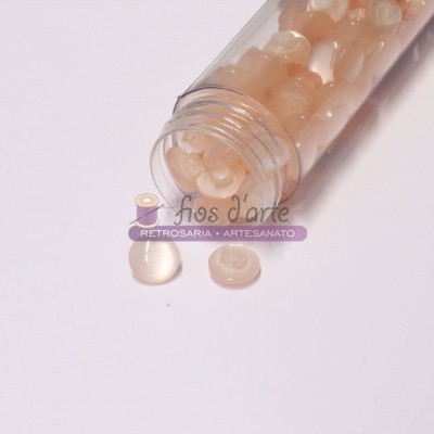 Frasco aberto com contas peroladas bege claro sobre fundo branco