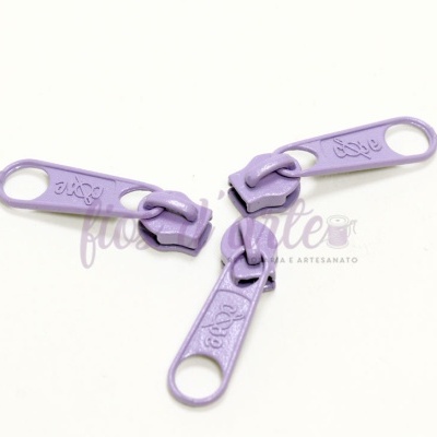 Três puxadores de fecho éclair lilás sobre fundo branco