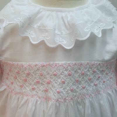 vestido branco de bebê com bordado rosa na cintura e gola com bordado branco