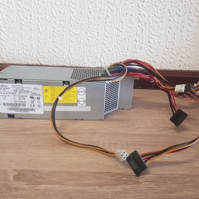 Fonte de alimentação para computador com cabos coloridos numa superfície de madeira