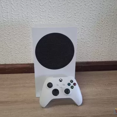 Consola Xbox Série S branca com controlador branco sobre chão de madeira