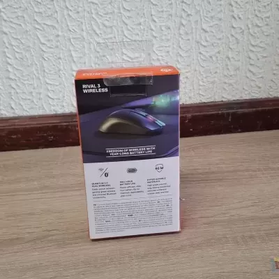 Embalagem de rato wireless branca e laranja sobre chão de madeira clara