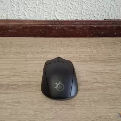 Rato de computador preto SteelSeries sobre superfície de madeira clara