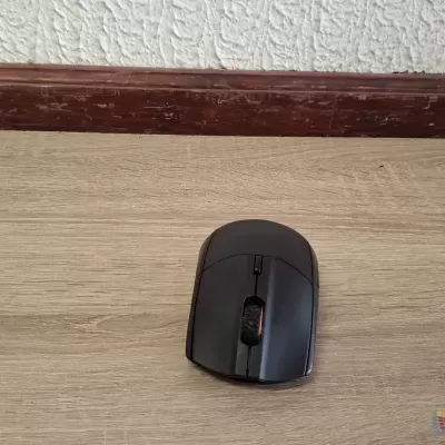 Rato de computador preto sobre mesa de madeira clara com parede branca ao fundo