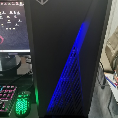 Computador desktop preto com luz azul ao lado de teclado iluminado