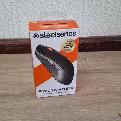 Embalagem de rato gaming SteelSeries Rival 3 Wireless sobre chão de madeira clara