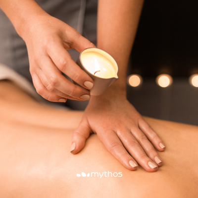 Mão segurando vela acesa sobre costas de pessoa deitada