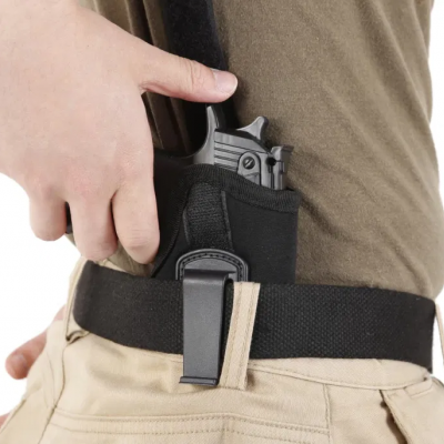 Pistola preta a ser colocada em coldre preto de tecido preso a cinto