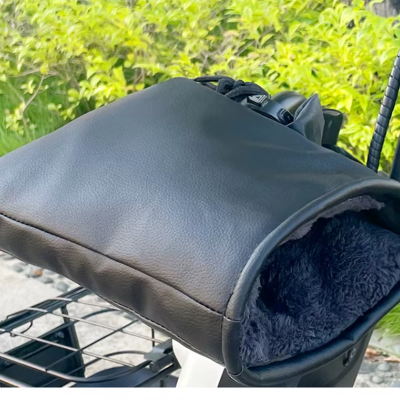 luvas de mãos pretas em pele sintética com interior felpudo cinza na estrutura de uma bicicleta