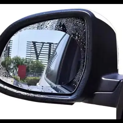 Espelho retrovisor de carro preto com gotas de água refletindo uma estrada urbana